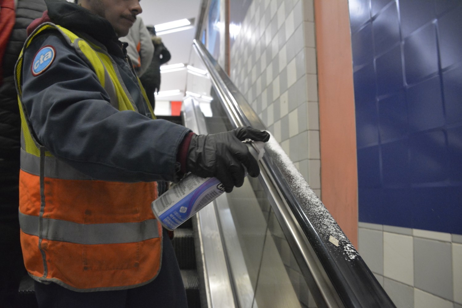 A CTA worker disinfects an escalator railing. Photo: CTA