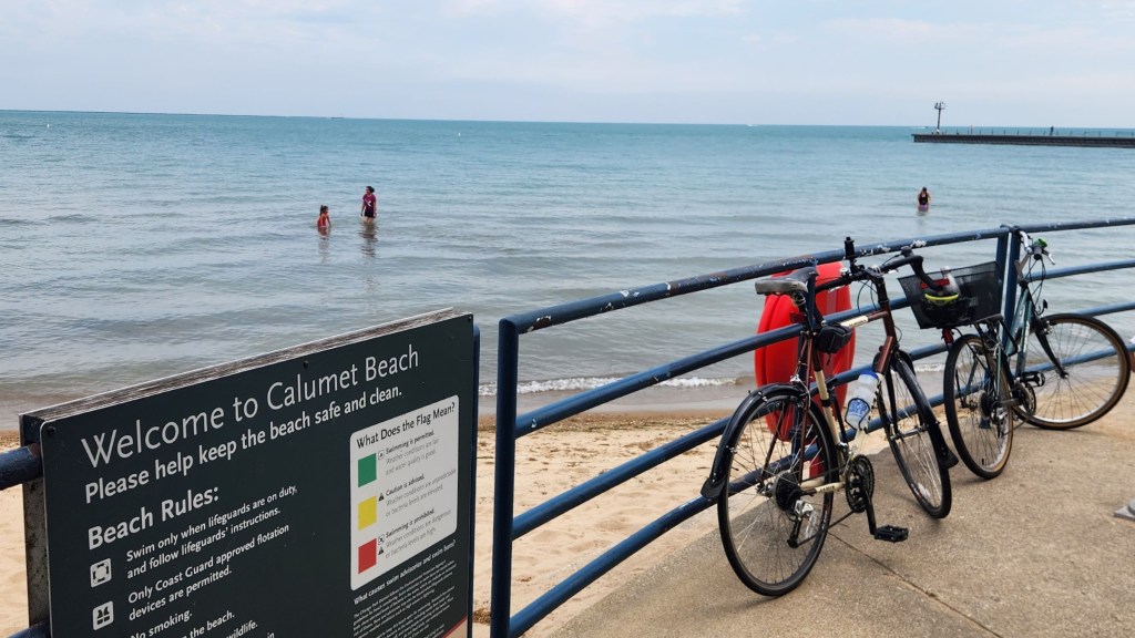 Two bicycles locked to a metal fence overlooking Calumet Park Beach